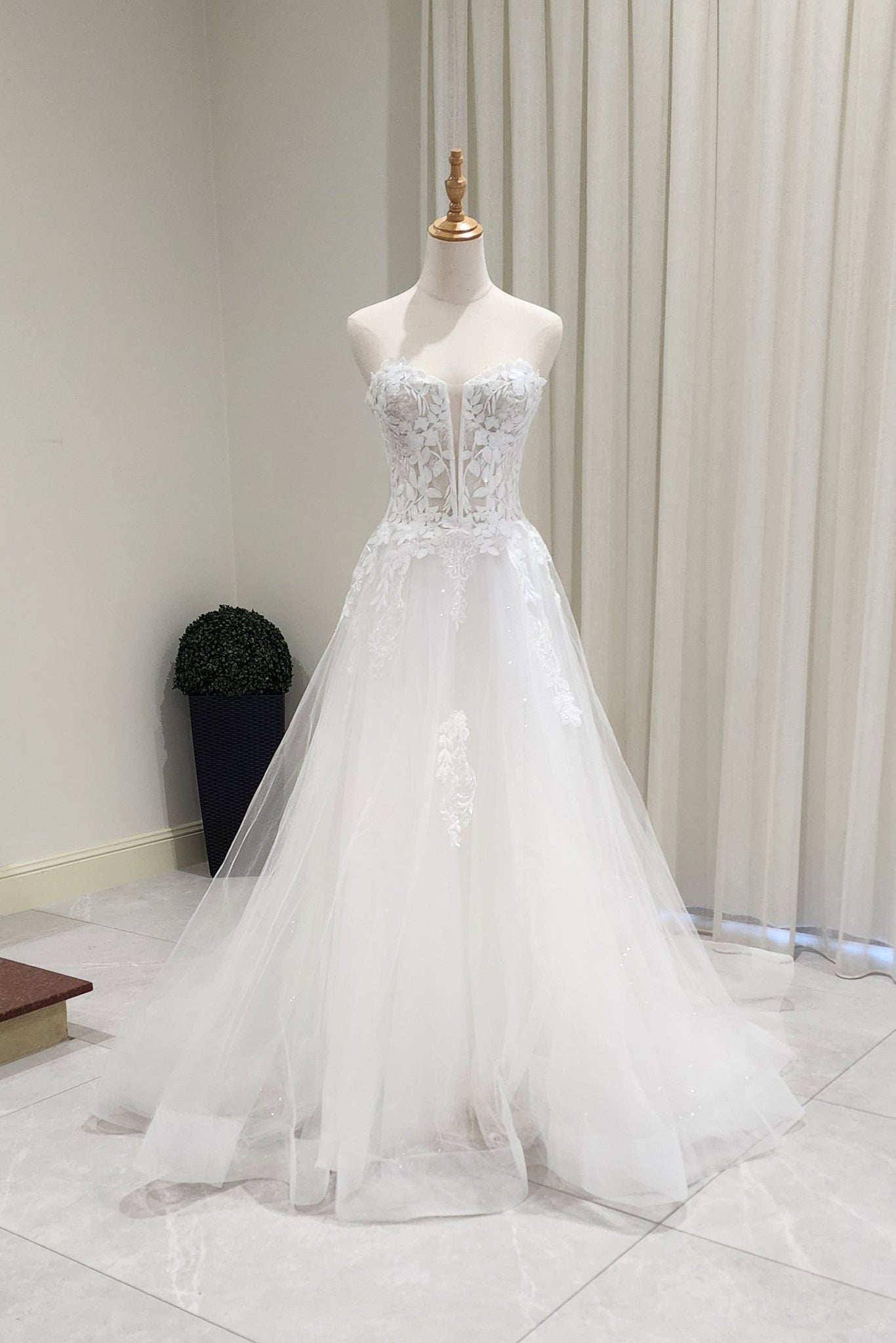White wedding dress on a mannequin against a neutral background