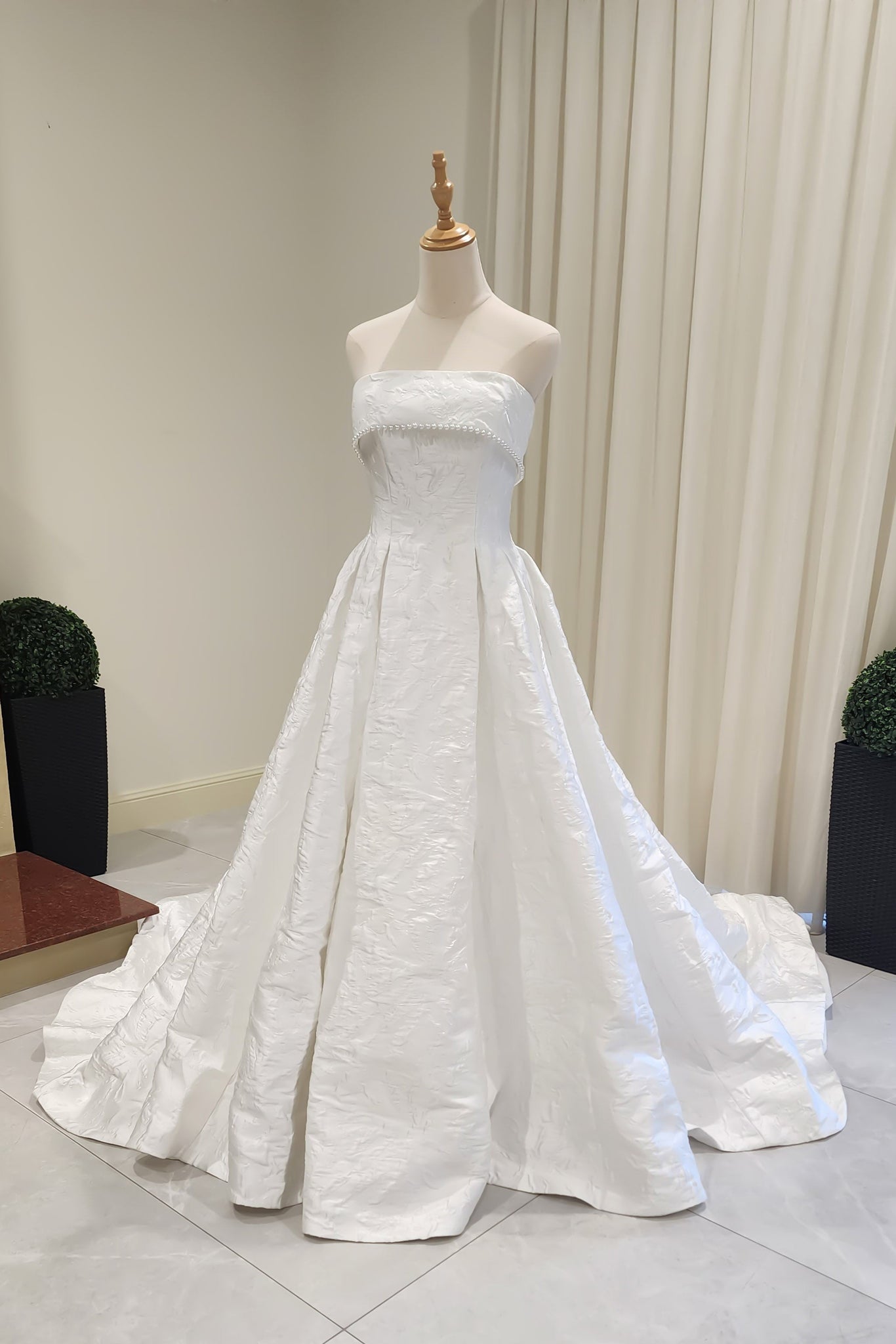 White strapless gown on a mannequin against a neutral background