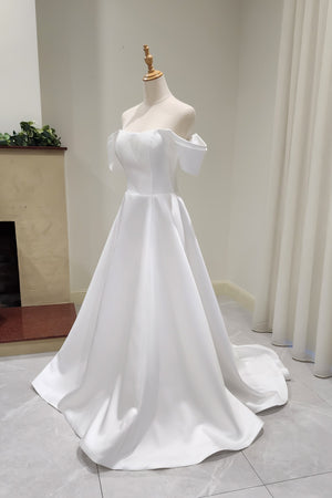 White off-shoulder wedding dress on a mannequin against a neutral background