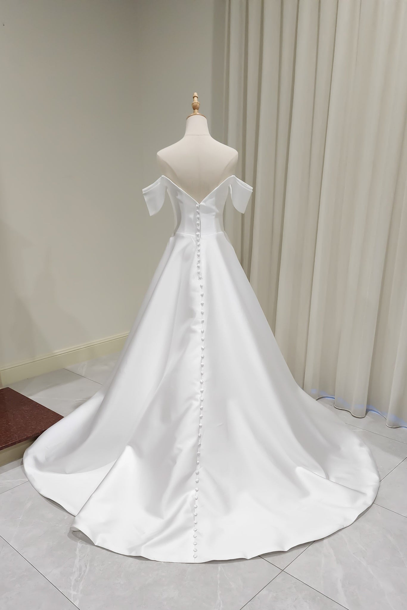 White wedding dress on a mannequin against a neutral background