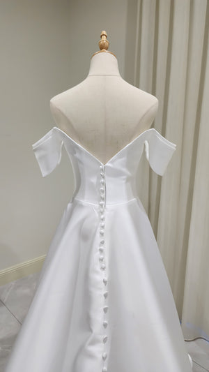 White off-shoulder dress on a mannequin against a neutral background