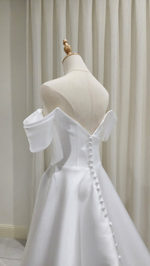 White off-shoulder dress on a mannequin against a neutral background