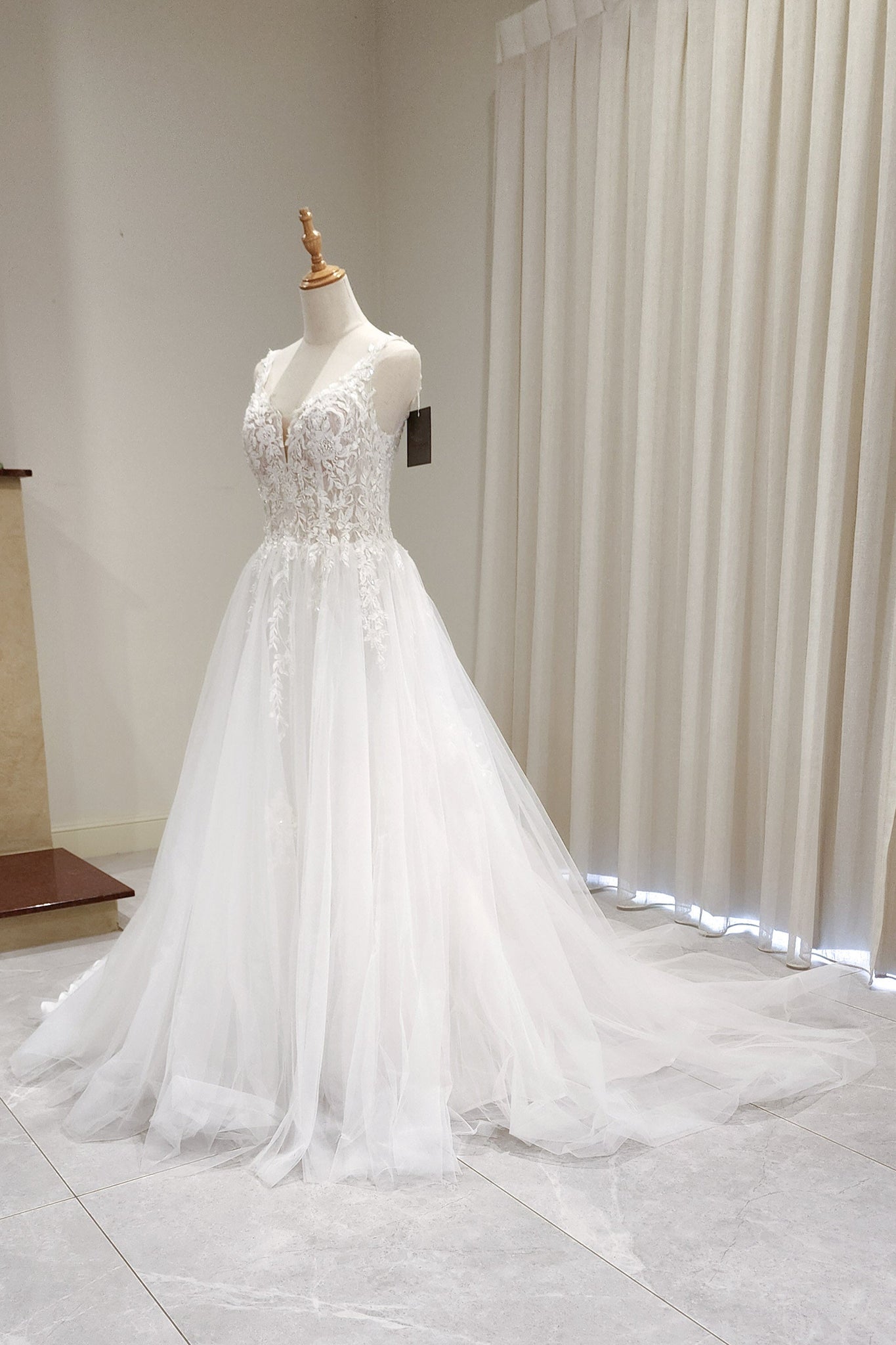White wedding dress on a mannequin against a neutral background